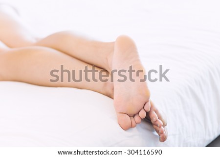 Asia Young woman lying in bed in home with closeup of bare feet
