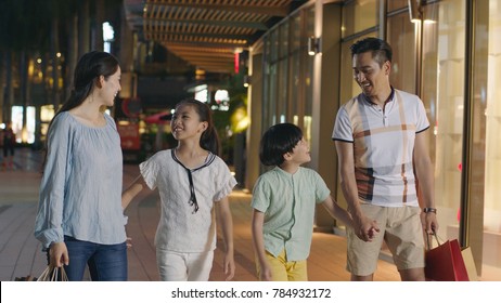 Asiam Family Laughing & Walking Outside Shopping Mall At Night