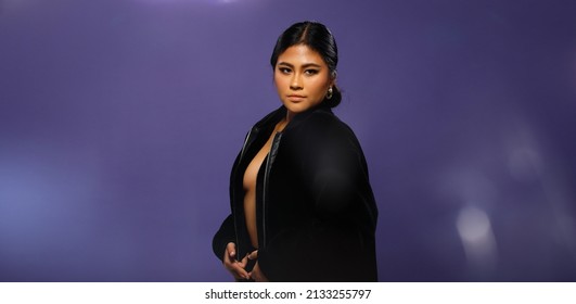 Asian 20s Woman Chubby Wear Black Fur Jacket And Unzip To Show Sexy Breast Over Purple Background. Half Body Female Black Hair Express Feeling Strong Smile On Face Eyes In Studio Lighting