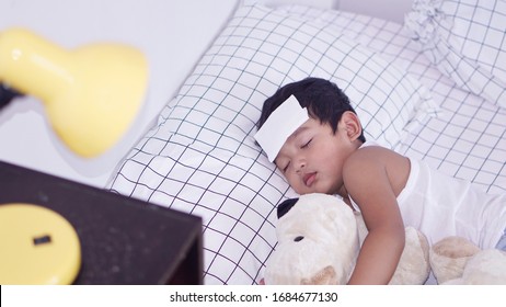 Asian 2-3 Years Old Toddler Boy Child Gets High Fever Lying On Bed With Cold Compress, Wet Washcloth On Forehead To Relieve Pain, Cool A Fever, Cold, Flu Treatment In Children, Home Remedies Concept. 