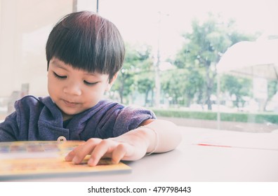 Asian 3 Year Old Boy Is Reading Picture Book With Copy Space.