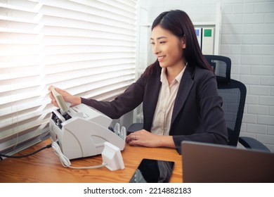 Asian accountant businesswoman using banknote counter machine counting money bill cash in office, financial preparing tax returns and accounts, monitoring expenditures and budget, auditing analyzing. - Powered by Shutterstock