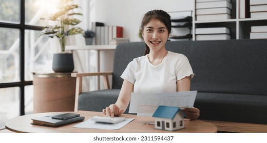 Asian accounting professional calculating household bills, reviewing and analyzing household bills, and filing tax returns - Shutterstock ID 2311594437