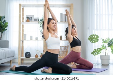 Asian active woman friend doing Yoga Pilates workout together at home. Attractive girl in sportswear using mat spend free leisure time exercise for health care and wellness a in living room at house. - Powered by Shutterstock