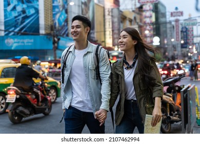 Asian Active Young Couple Travel In City For Honeymoon Trip At Night. Attractive New Marriage Man And Woman Backpacker Tourist Walking On Street Enjoy Spend Time Dating On Valentines Vacation Together