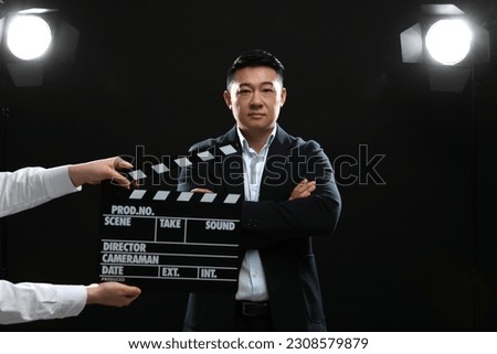 Asian actor performing while second assistant camera holding clapperboard on stage. Film industry