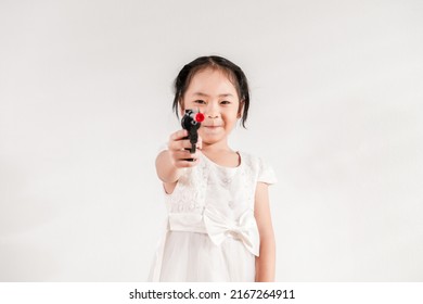 Asian Adorable Little Kid Toddler Girl Funny Play Pointing A Gun To The Camera A Selective Focus. Kid And Children Safety To Avoid Neighborhood School Violence In The Future Concept Ideas.