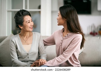 asian adult daughter sitting on couch at home chatting conversing with senior mother happy and smiling - Powered by Shutterstock