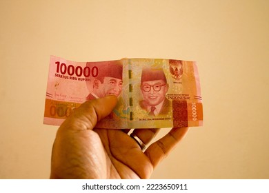 Asian Adult Male Left Hand Holding Indonesian Rupiah (100 Thousand Nominal)