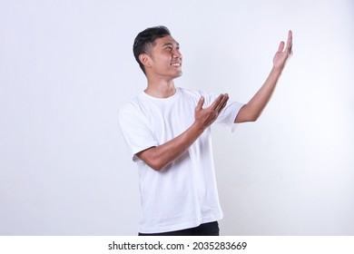 An Asian Adult Man Wearing A White T-shirt Looks On And Opens His Arms To The Side With A Smiling Face On A White Background.