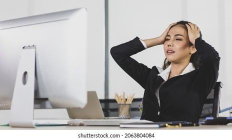 Asian adult woman is office people are serious sitting at work desk look feel to disappointed with working job.