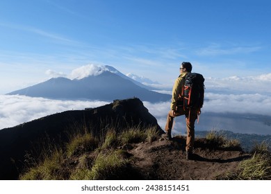 Asian Adventure, Man Model on Mountain Summit, Carrying Hiking Gear under Blue Sky above Ocean of Clouds - Powered by Shutterstock