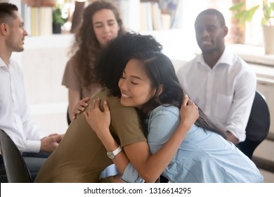 Asian and african women embracing giving psychological support during group therapy counseling session, diverse ladies hug sit in circle feel relief empathy helping friend at with problems addiction