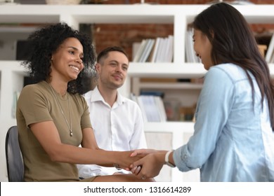 Asian and african women holding hands during group therapy session, diverse friends feeling reconciled relief smiling giving psychological support empathy overcome problem at psychotherapy counseling - Powered by Shutterstock