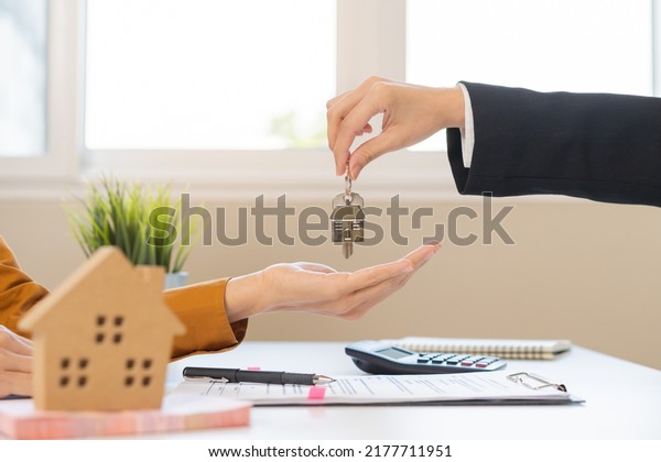 Asian agent giving a key to new owner or tenant,\
client after signed signature contract rental purchase, buyer\
apartment, home with landlord, realtor. Banker agreement mortgage\
loan. Property lease.