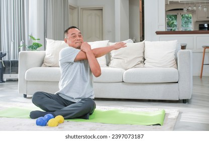 Asian aging senior old man wearing casual comfortable t shirt, sitting on floor in living room at cozy home, doing exercise with happiness, smiling. Healthcare, Retirement Concept - Powered by Shutterstock