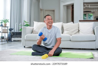 Asian aging senior old man wearing casual comfortable t shirt, sitting on floor in living room at cozy home, doing exercise with happiness, smiling. Healthcare, Retirement Concept - Powered by Shutterstock