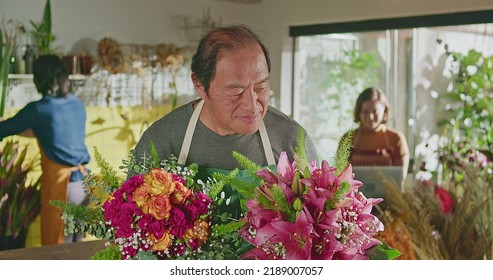 Asian American Business Entrepreneur Owner Of Flower Shop Standing Holding Two Bouquet Of Flower Arrangements Smiling At Camera