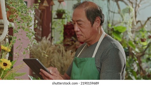 An Asian American Business Owner Using Tablet Technology Inside Small Business Store Checking Inventory Online