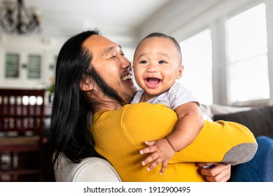 Asian American father hugging his little son