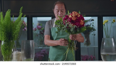 An Asian American Florist Preparing Bouquet Of Flowers For Online Delivery. Portrait Of An Artisan Male Florist Creating Artistic Arrangement For Client At Flower Shop