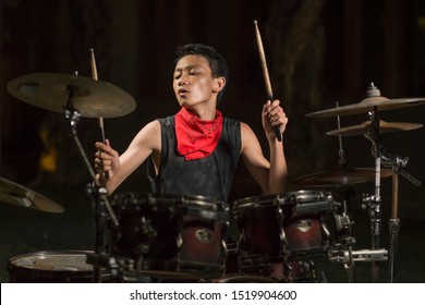 Asian American Mixed Teenager Playing Drums At Home Garden . Cool And Handsome Young Boy Practicing On Drum Kit Rehearsing Passionate In Badass Rock Band Look Enjoying The Practice