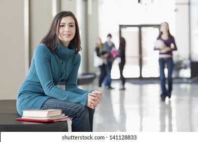 Asian American Student Seated At Table With Books In Library