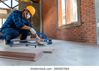 Asian artisan tiler at construction site, worker cuts a large slab of tile during the construction of a house, floor tile cutting equipment