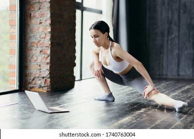 Asian Athlete Lunges To The Side To Stretch The Hamstrings And Inner Thigh. Online Training Via Laptop.