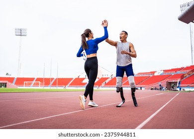 Asian athlete with prosthetic blades and trainer workout in stadium. Attractive amputee male runner and young sportswoman feel happy and enjoy practicing workout for Paralympics running competition.