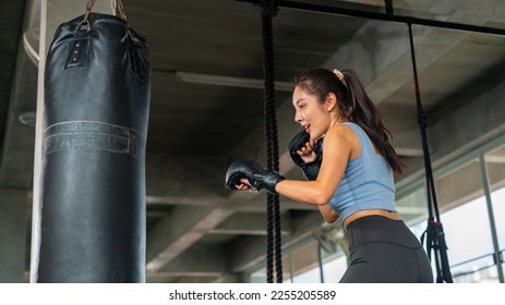 Asian athlete woman in sportswear and boxing gloves do workout boxing exercise with punching bag at gym. Healthy girl do sport training and body building at fitness. Health care motivation concept. - Powered by Shutterstock