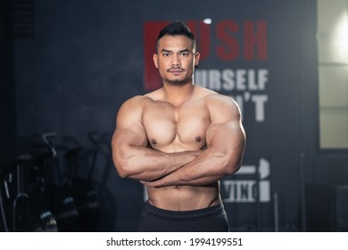 Asian attractive Active Fitness sportman trainer workout exercise to maintain muscle and biceps for health. Bodybuilder athlete male stand with arm crossed and smile, look at camera in stadium or gym. - Powered by Shutterstock