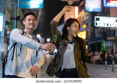 Asian attractive couple drinking alcohol and having party together. Young man and woman tourist travel in city spend time on holiday vacation together holding bottle of beer at dark night on the road. - Powered by Shutterstock