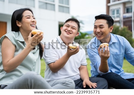 Asian attractive family, parents playing with young son in the garden. Beautiful loving couple, father and mother support take care young happy man special needs person outdoors in backyard at home.