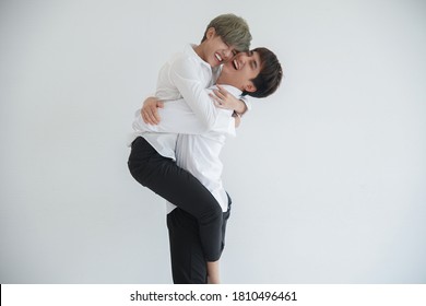 Asian Attractive Lgbt Young Gay Couple Riding On Back And Hugging Kissing In The Room On White Background