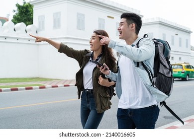 Asian attractive romantic couple travel in the city for honeymoon trip. New marriage man and woman backpacker tourist use mobile phone find destination, enjoy spend time on holiday vacation together.