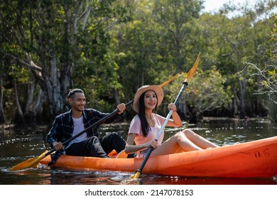 Asian Attractive Romantic Young Couple Rowing Kayak In A Forest Lake. Backpacker Man And Woman Travel And Kayaking On Canoe In Beautiful Mangrove Forest Enjoy Spend Time On Holiday Vacation Together.