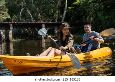 Asian Attractive Romantic Young Couple Rowing Kayak In A Forest Lake. Backpacker Man And Woman Travel And Kayaking On Canoe In Beautiful Mangrove Forest Enjoy Spend Time On Holiday Vacation Together.