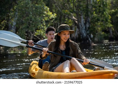 Asian Attractive Romantic Young Couple Rowing Kayak In A Forest Lake. Backpacker Man And Woman Travel And Kayaking On Canoe In Beautiful Mangrove Forest Enjoy Spend Time On Holiday Vacation Together.