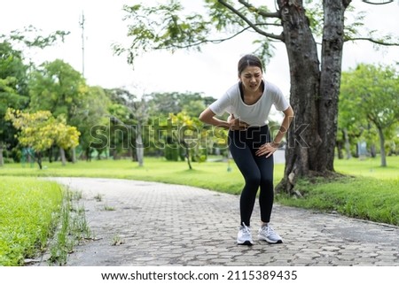 Asian attractive sport woman feels pain on stomach after run on street.Beautiful girl athlete in sportswear having stomach ache illness problem while exercise by jogging workout in outdoor public park