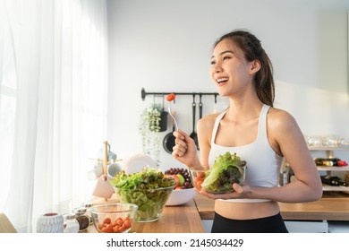 Asian attractive sport woman holding salad bowl and eat vegetables. Beautiful sport girl in sportswear enjoy eat clean vegetables after exercise for health in house. Diet and Healthy food concept. - Shutterstock ID 2145034429