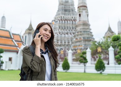 Asian Attractive Woman Backpacker Talking On Phone While Walk In City. Beautiful Woman Tourist Traveler Travel Alone On Street Using Smartphone Enjoy Spend Time On Holiday Vacation Trip In Thailand.