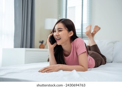 Asian attractive woman use mobile phone chat on bed at home in morning. Happy casual beautiful female lying down in bedroom enjoy holiday weekend, use smartphone communicate with technology in house.
 - Powered by Shutterstock