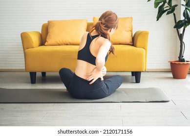 Asian attractive young woman, is currently having a waist pain During  exercise in home, due to osteoarthritis, to sports and health care concept.