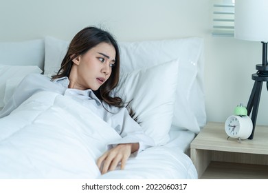 Asian Attractive Young Woman Feel Shock After Wake Up Late In Bedroom. Beautiful Girl In Pajamas Look At Alarm Clock And Awake From Sleep In Hurry And Fast Due To Oversleep In Morning On Bed At Home.