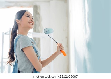 Asian attractive Young asian woman smiling cheerful happy female painting new home interior wall with paint roller in new house, Home relocation and renovation decoration daytime concept - Powered by Shutterstock