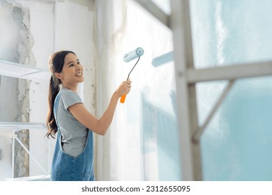 Asian attractive Young asian woman smiling cheerful happy female painting new home interior wall with paint roller in new house, Home relocation and renovation decoration daytime concept - Powered by Shutterstock