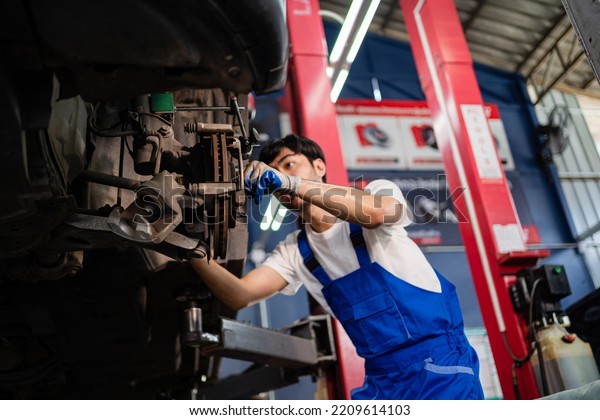 Asian auto mechanic in car garage. Vehicle service\
personnel are inspecting cars in mechanic factory with confidence\
in car engine repairs. Asian mechanic with equipment to fix cars in\
the service. 