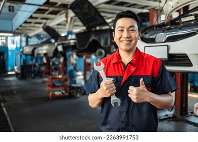 Asian  automotive engineer people wear helmet work in mechanics garage.young auto mechanic in uniform is looking at camera and smiling examining car. - Powered by Shutterstock