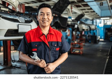 Asian  automotive engineer people wear helmet work in mechanics garage.young auto mechanic in uniform is looking at camera and smiling examining car. - Powered by Shutterstock